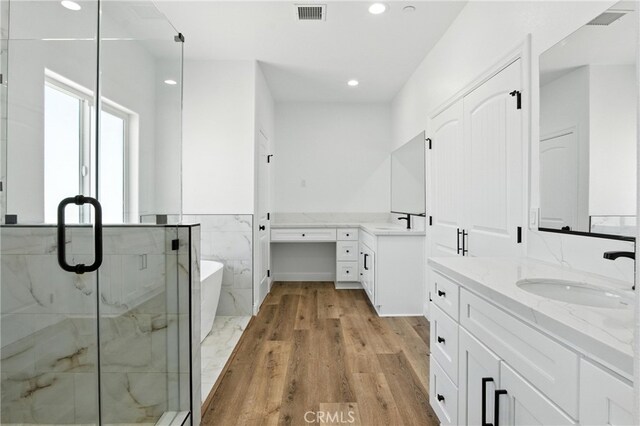 15323 Turquoise Rd, Apple Valley, CA 92307 - bathroom featuring two vanities, a marble finish shower, a freestanding tub, recessed lighting, and wood finished floors