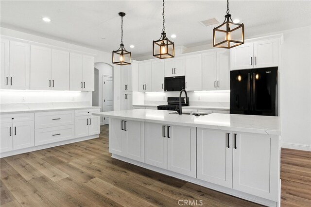 15323 Turquoise Rd, Apple Valley, CA 92307 - kitchen featuring black appliances, arched walkways, recessed lighting, white cabinets, and a center island with sink