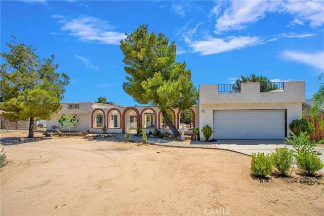 7165 Lyons Ave, Hesperia, CA 92345 - mediterranean / spanish house with stucco siding, a garage, dirt driveway, and a balcony