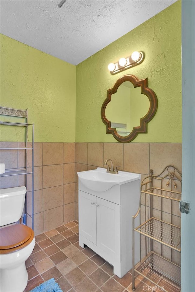 7165 Lyons Ave, Hesperia, CA 92345 - bathroom with a textured wall, tile walls, vanity, a textured ceiling, and wainscoting