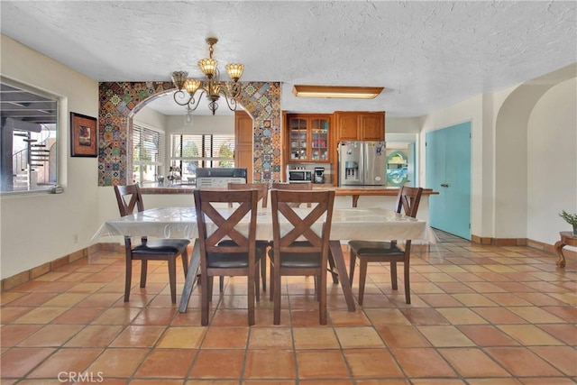 7165 Lyons Ave, Hesperia, CA 92345 - dining area featuring arched walkways, a textured ceiling, a chandelier, and light tile patterned flooring