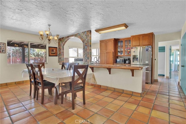 7165 Lyons Ave, Hesperia, CA 92345 - dining area featuring arched walkways, a chandelier, light tile patterned floors, and a textured ceiling