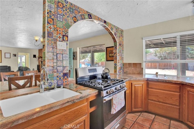 7165 Lyons Ave, Hesperia, CA 92345 - kitchen with gas range, a textured ceiling, arched walkways, open floor plan, and light stone counters