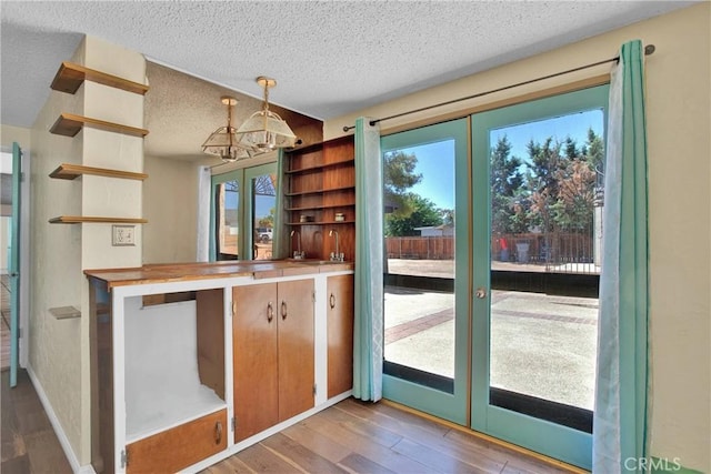 7165 Lyons Ave, Hesperia, CA 92345 - kitchen featuring open shelves, french doors, a textured ceiling, wood finished floors, and a chandelier