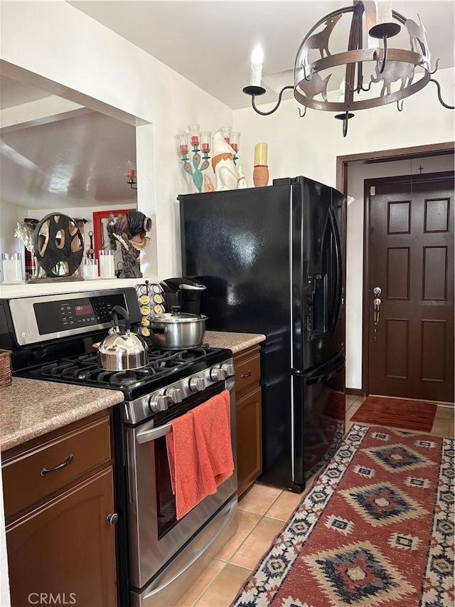 10914 S Osage Ave, Inglewood, CA 90304 - kitchen with stainless steel range with gas stovetop, light tile patterned floors, a chandelier, light countertops, and black refrigerator with ice dispenser