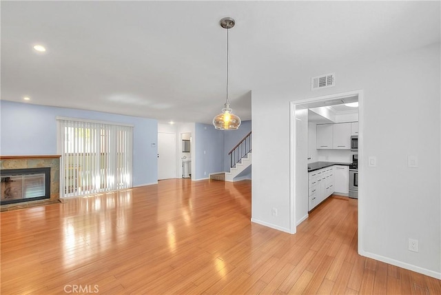 11154 Huston St Unit 7, North Hollywood, CA 91601 - unfurnished living room with stairs, light wood-style floors, a tile fireplace, and recessed lighting