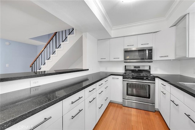 11154 Huston St Unit 7, North Hollywood, CA 91601 - kitchen featuring appliances with stainless steel finishes, white cabinets, light wood-style floors, ornamental molding, and dark stone countertops