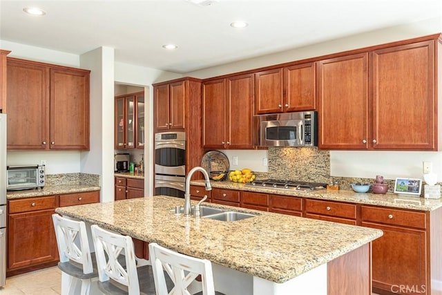 17122 Broken Rock Ct, Riverside, CA 92503 - kitchen with stainless steel appliances, a kitchen bar, an island with sink, recessed lighting, and light stone counters