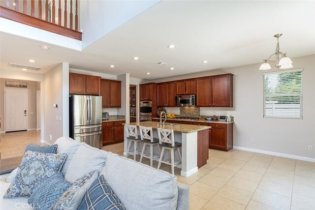 17122 Broken Rock Ct, Riverside, CA 92503 - kitchen with stainless steel appliances, open floor plan, light tile patterned flooring, a breakfast bar, and recessed lighting