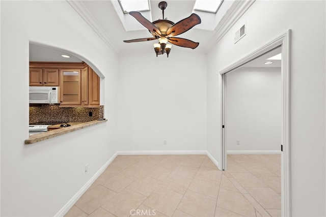 456 Avenida Seville Unit C, Laguna Woods, CA 92637 - unfurnished dining area featuring ornamental molding, a skylight, a ceiling fan, recessed lighting, and arched walkways
