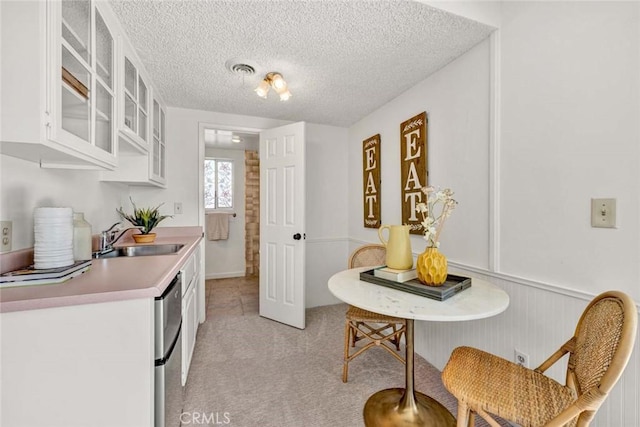 1428 E Adams Ave, Orange, CA 92867 - kitchen with light countertops, white cabinetry, a textured ceiling, glass insert cabinets, and light carpet