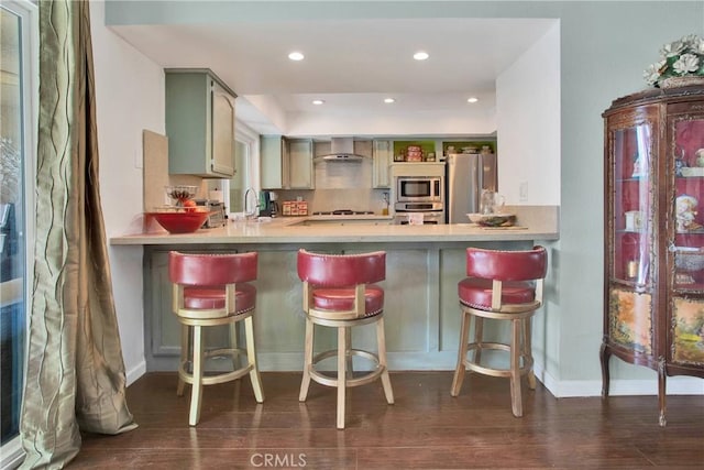 15037 Wildflower Ln, Helendale, CA 92342 - kitchen with stainless steel appliances, dark wood-type flooring, a peninsula, wall chimney range hood, and recessed lighting