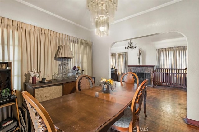1636 W 70th St, Los Angeles, CA 90047 - dining area featuring arched walkways, wood finished floors, a fireplace, crown molding, and a chandelier