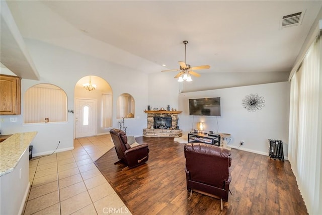 8225 Ailanthus St, Phelan, CA 92371 - living area with arched walkways, a ceiling fan, a fireplace, vaulted ceiling, and light tile patterned floors