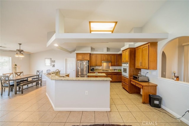 8225 Ailanthus St, Phelan, CA 92371 - kitchen with freestanding refrigerator, oven, light tile patterned floors, brown cabinets, and vaulted ceiling