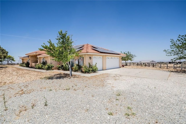8225 Ailanthus St, Phelan, CA 92371 - view of front of property featuring roof mounted solar panels, a tile roof, stucco siding, and concrete driveway
