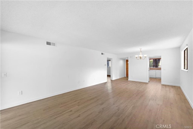 31291 E Nine Dr Unit 29F, Laguna Niguel, CA 92677 - unfurnished living room with a chandelier, wood finished floors, and a textured ceiling