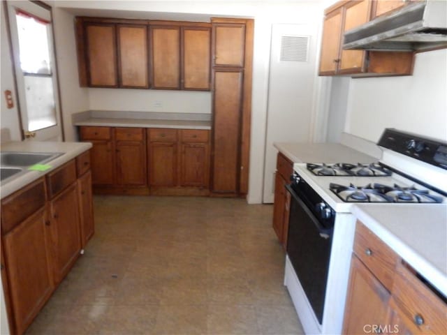3250 Apple Ave, Jurupa Valley, CA 92509 - kitchen with white gas stove, under cabinet range hood, brown cabinetry, and light countertops