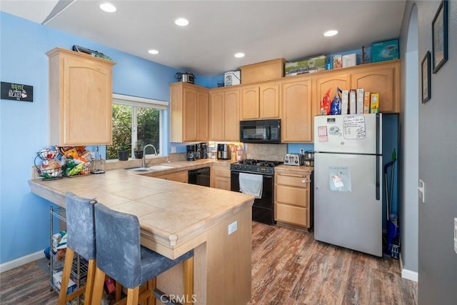 1681 Ocean St, Oceano, CA 93445 - kitchen featuring black appliances, light brown cabinets, a peninsula, dark wood-type flooring, and a breakfast bar