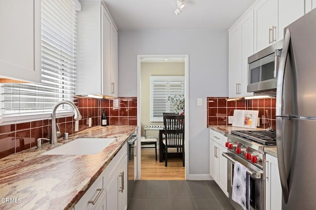 324 N J St, Oxnard, CA 93030 - kitchen with stainless steel appliances, dark tile patterned flooring, white cabinets, decorative backsplash, and light stone counters
