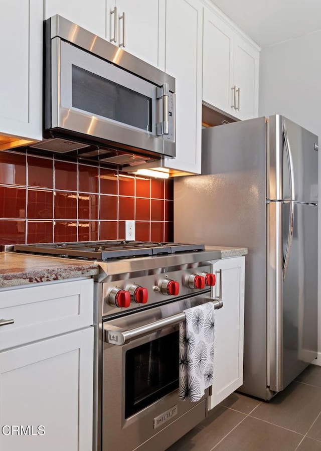 324 N J St, Oxnard, CA 93030 - kitchen with appliances with stainless steel finishes, tile patterned floors, white cabinetry, tasteful backsplash, and light stone counters