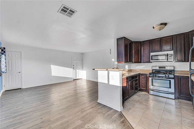 5224 Denny Ave Unit 209, North Hollywood, CA 91601 - kitchen with stainless steel appliances, dark brown cabinetry, open floor plan, light wood-style floors, and a peninsula