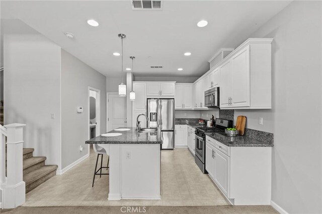 2894 E Via Fiano, Ontario, CA 91764 - kitchen with stainless steel appliances, white cabinets, a kitchen bar, pendant lighting, and dark stone counters