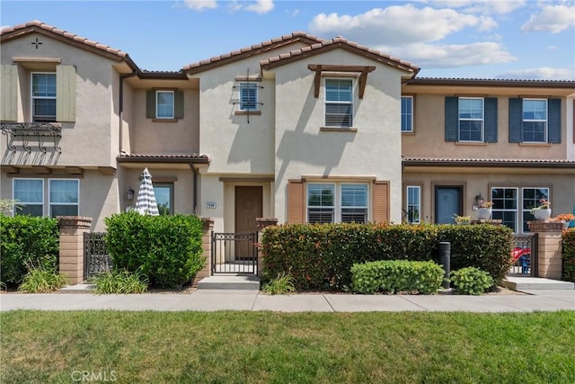 2894 E Via Fiano, Ontario, CA 91764 - view of front of home with stucco siding, a tiled roof, a front yard, and a gate