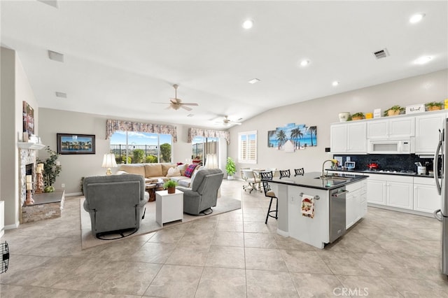 33818 Channel St, Temecula, CA 92592 - kitchen with white microwave, dishwasher, dark countertops, open floor plan, and tasteful backsplash