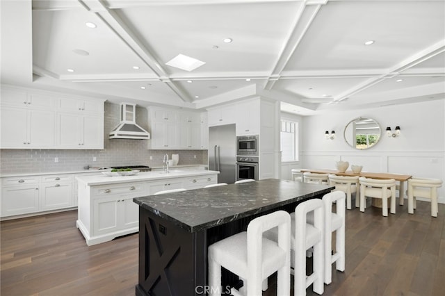 1456 Key Vw, Corona Del Mar, CA 92625 - kitchen featuring wall chimney exhaust hood, an island with sink, coffered ceiling, appliances with stainless steel finishes, and dark wood-style flooring