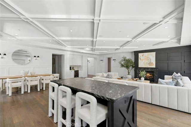 1456 Key Vw, Corona Del Mar, CA 92625 - kitchen with a decorative wall, coffered ceiling, light wood-style flooring, a lit fireplace, and a center island