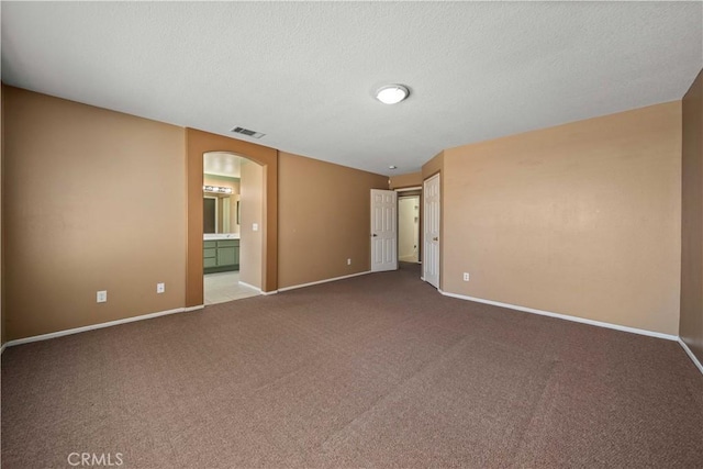 5715 Malaga Ct, Palmdale, CA 93552 - unfurnished bedroom featuring arched walkways, carpet, a textured ceiling, and connected bathroom