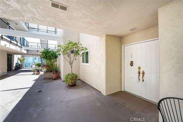 2385 Via Mariposa Unit 1F, Laguna Woods, CA 92637 - view of exterior entry with stucco siding and a patio
