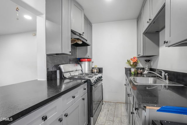 136 N Garfield Ave, Oxnard, CA 93030 - kitchen with range with gas cooktop, under cabinet range hood, dark stone counters, tasteful backsplash, and light wood-type flooring