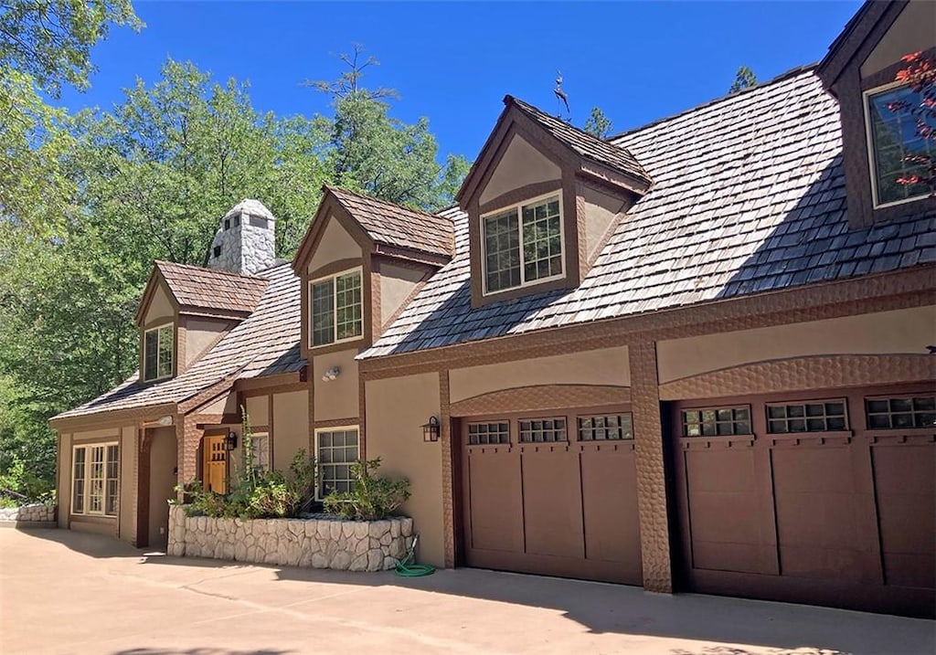 28971 N Shore Rd, Lake Arrowhead, CA 92352 - view of home's exterior with stucco siding, a chimney, and driveway