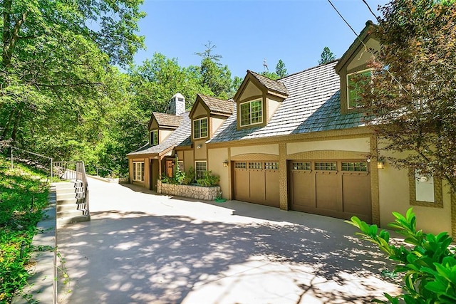 28971 N Shore Rd, Lake Arrowhead, CA 92352 - view of side of property with stucco siding, concrete driveway, a chimney, and an attached garage