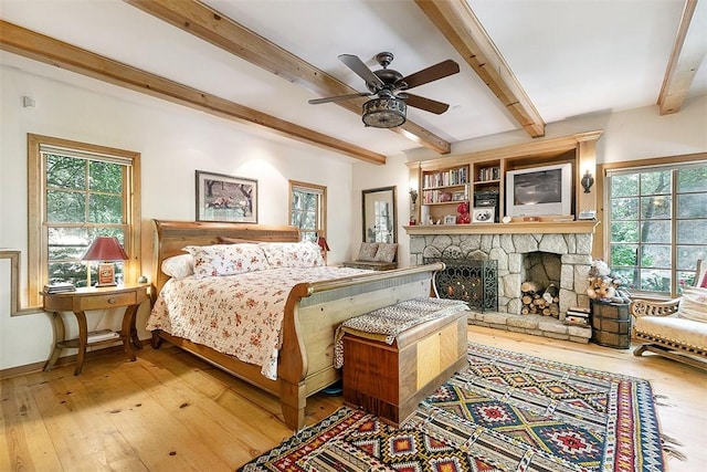 28971 N Shore Rd, Lake Arrowhead, CA 92352 - bedroom featuring multiple windows, hardwood / wood-style flooring, beamed ceiling, and a stone fireplace