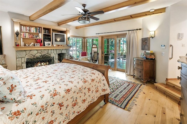 28971 N Shore Rd, Lake Arrowhead, CA 92352 - bedroom with access to exterior, hardwood / wood-style floors, beamed ceiling, a stone fireplace, and ceiling fan