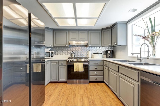 1998 Barnett Way, Los Angeles, CA 90032 - kitchen featuring stainless steel appliances, gray cabinets, under cabinet range hood, light wood-style flooring, and decorative backsplash