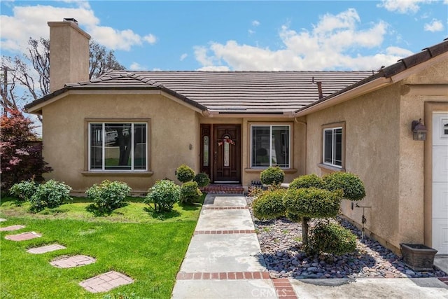 8291 Jennet St, Rancho Cucamonga, CA 91701 - property entrance with a chimney, a tile roof, a yard, and stucco siding