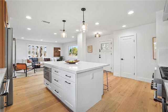 3119 Gibraltar Ave, Costa Mesa, CA 92626 - kitchen with a breakfast bar area, light wood-style floors, white cabinetry, recessed lighting, and light countertops