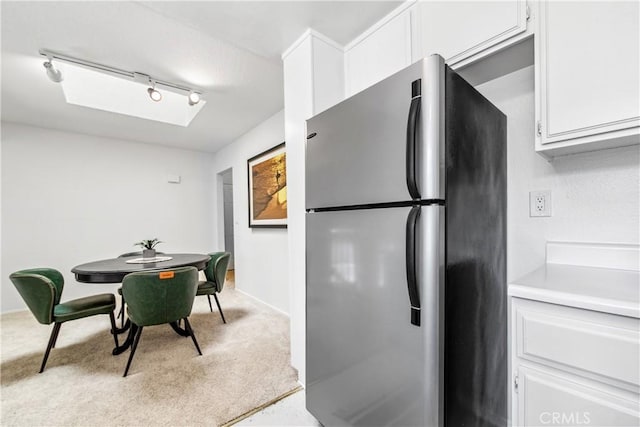 18051 Wakefield Ln Unit 106, Huntington Beach, CA 92648 - kitchen with freestanding refrigerator, rail lighting, carpet floors, white cabinetry, and light countertops