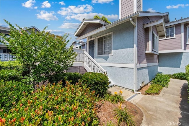 18051 Wakefield Ln Unit 106, Huntington Beach, CA 92648 - view of home's exterior featuring a chimney, stairway, and stucco siding