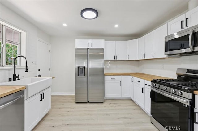 2422 E 115th St, Los Angeles, CA 90059 - kitchen featuring stainless steel appliances, wooden counters, tasteful backsplash, white cabinetry, and recessed lighting