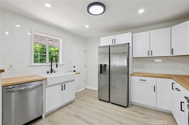 2422 E 115th St, Los Angeles, CA 90059 - kitchen featuring stainless steel appliances, wooden counters, decorative backsplash, white cabinetry, and recessed lighting