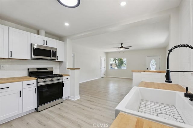 2422 E 115th St, Los Angeles, CA 90059 - kitchen with appliances with stainless steel finishes, wooden counters, light wood finished floors, tasteful backsplash, and recessed lighting