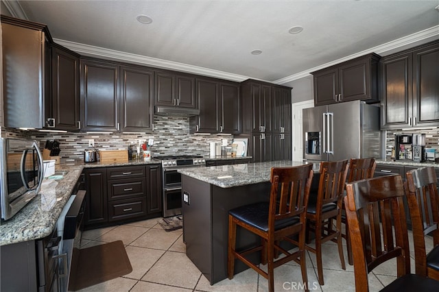 39269 Clear View Ct, Palmdale, CA 93551 - kitchen featuring appliances with stainless steel finishes, a center island, crown molding, under cabinet range hood, and decorative backsplash
