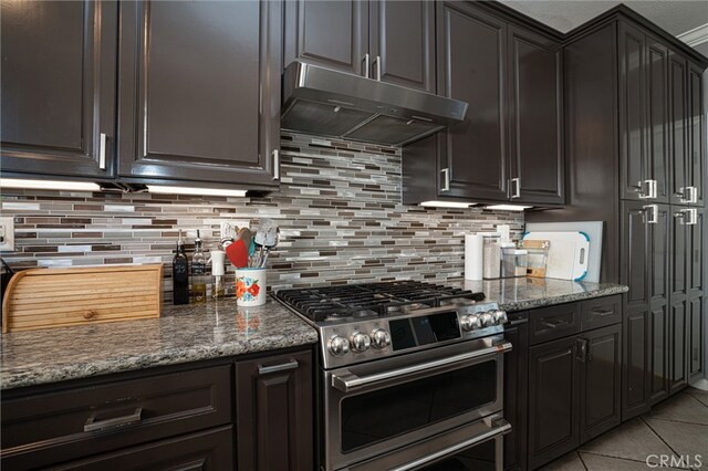 39269 Clear View Ct, Palmdale, CA 93551 - kitchen with double oven range, under cabinet range hood, backsplash, light tile patterned floors, and dark stone countertops
