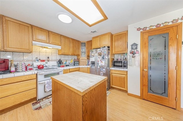 35095 Rough Rider Way, Raymond, CA 93653 - kitchen with appliances with stainless steel finishes, under cabinet range hood, light wood finished floors, tasteful backsplash, and tile counters
