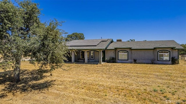 35095 Rough Rider Way, Raymond, CA 93653 - ranch-style home with covered porch, solar panels, a front yard, stucco siding, and a chimney